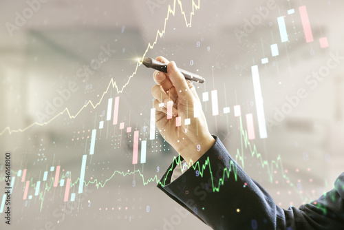 Man hand with pen working with abstract virtual financial graph on blurred office background, forex and investment concept. Multiexposure photo