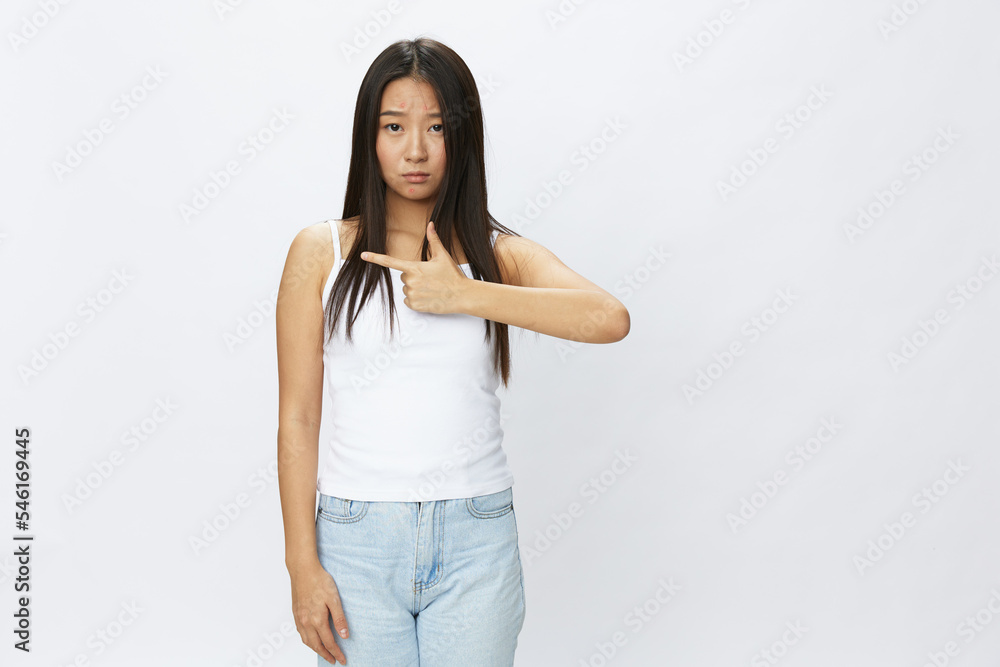Asian woman hand signals, finger pointing facial skin problems, acne and inflammation, red rash and allergies, chicken pox, sadness from rashes. Facial skin care concept for diseases and nerves Asian woman hand signals, finger pointing facial skin problems, acne and inflammation, red rash and allergies, chicken pox, sadness from rashes. Facial skin care concept for diseases and nerves