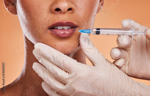 Woman, lips and hands for plastic surgery injection, botox or skincare treatment against a studio background. Hand of medical expert injecting female mouth in cosmetic surgery for fillers or implants