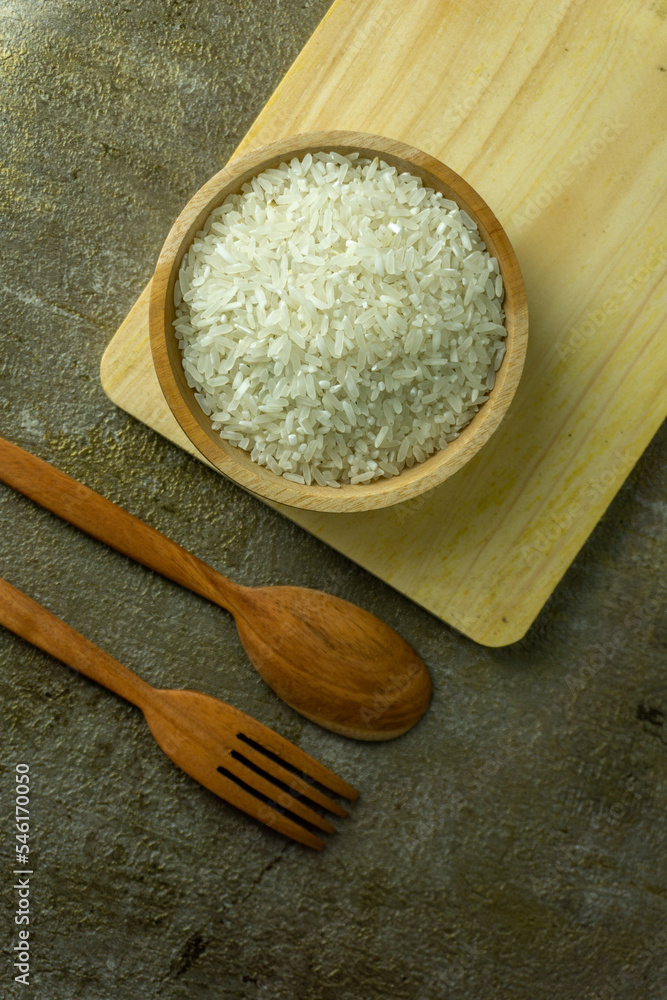 uncooked rice or dry rice. raw rice in wooden bowl with wooden spoon and fork uncooked rice or dry rice. raw rice in wooden bowl with wooden spoon and fork