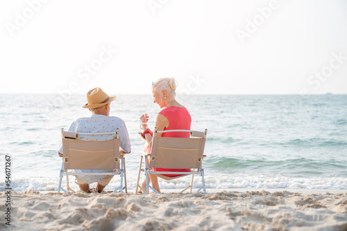 Happy senior couple sitting on a chair on the shore of the beach, activity after retirement in vacations and summer.