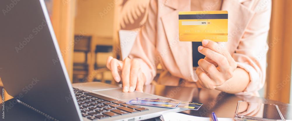 Woman holding credit cards and using laptops shopping online.