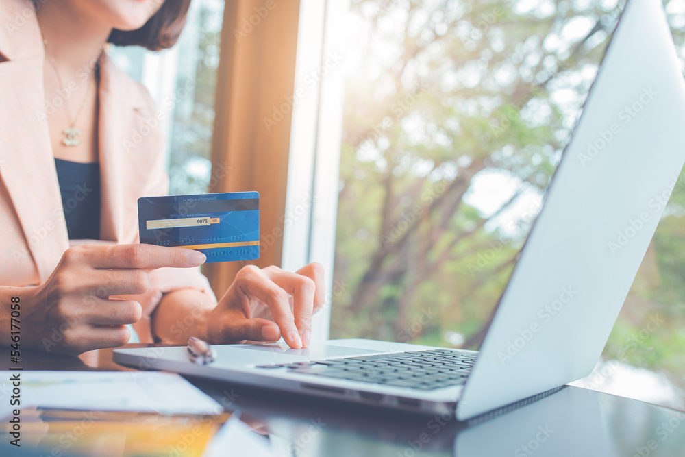 Woman holding credit cards and using laptops shopping online.