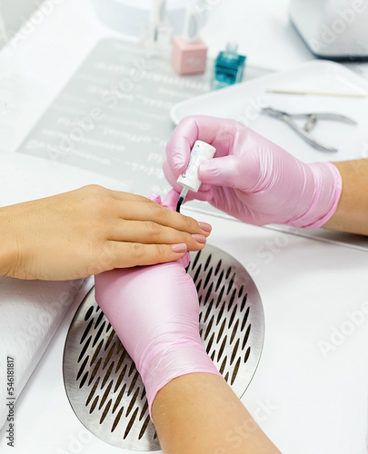 Closeup shot of a woman in a nail salon receiving a manicure by a beautician with nail file. Woman getting nail manicure. Beautician file nails to a customer. photo