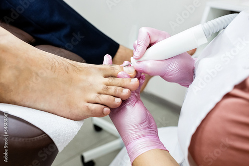 Close-up Of A Beautician Hand Filling Person's Nail In Salon