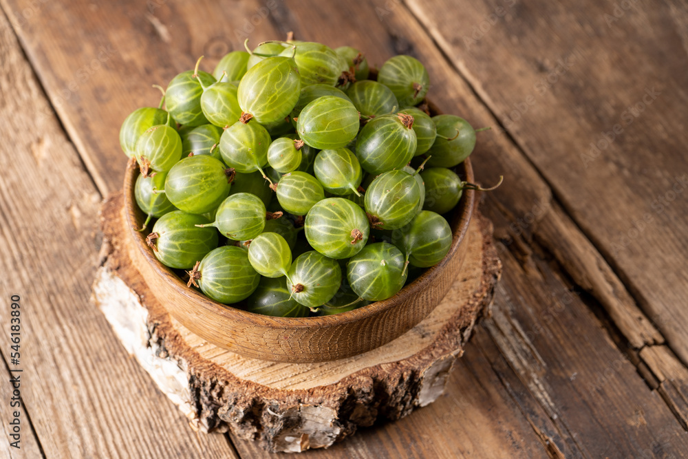 Green gooseberries in a wooden bowl. Harvest berries on a wooden table. Gooseberry summer vitamin food. Green gooseberries in a wooden bowl. Harvest berries on a wooden table. Gooseberry summer vitamin food.