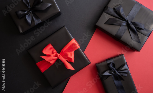 Gift box wrapped in red and black paper with a bow. Red, black background. Holiday concept. Place for text or advertising. Christmas. Valentine's Day.