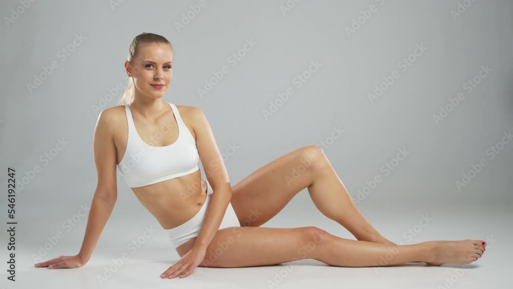 Young, fit and beautiful blond woman in white swimsuit posing over grey background. Healthcare, diet, sport and fitness concept. Young, fit and beautiful blond woman in white swimsuit posing over grey background. Healthcare, diet, sport and fitness concept.