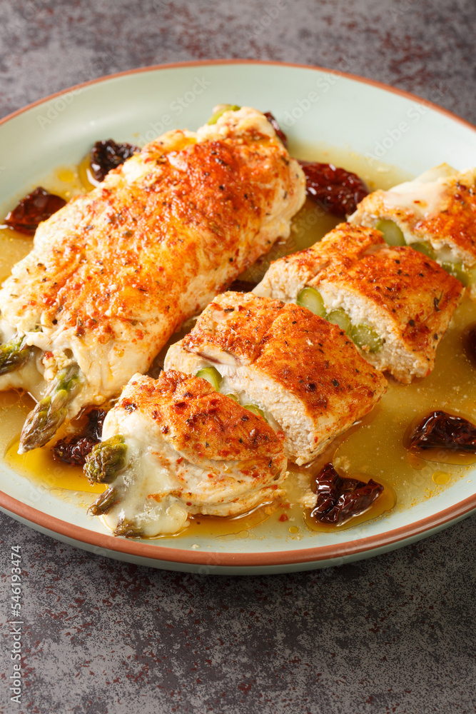 Asparagus and cheese stuffed chicken that has just come from the grill close-up in a plate on the table. Vertical Asparagus and cheese stuffed chicken that has just come from the grill close-up in a plate on the table. Vertical