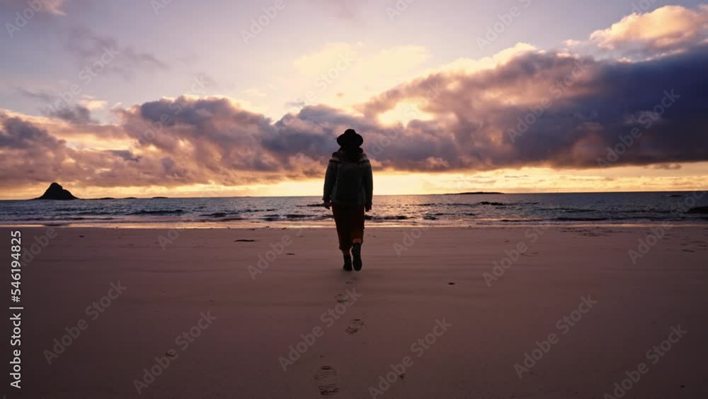 Silhouette of a girl in a hat with a backpack at sunset near the beach by the ocean Silhouette of a girl in a hat with a backpack at sunset near the beach by the ocean