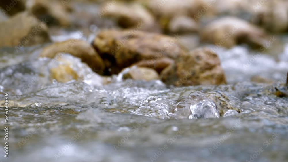 Clear stream running through stone boulders Abundant river flowing in slow motion. Wild mountain river water splashing in summer near the river bank environment. Clear stream running through stone boulders Abundant river flowing in slow motion. Wild mountain river water splashing in summer near the river bank environment.