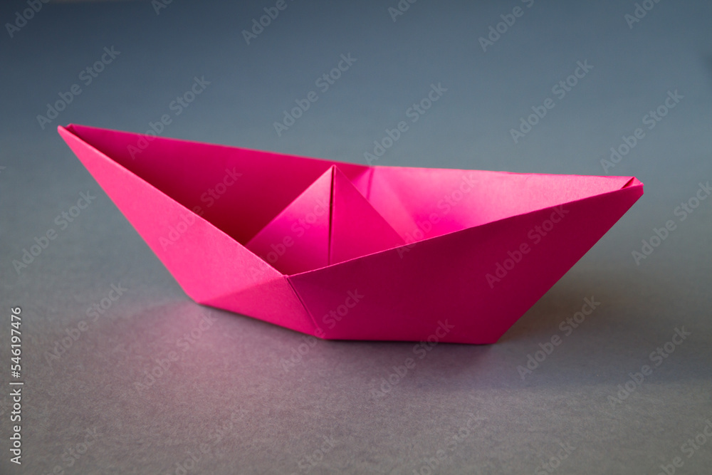 Pink paper boat origami isolated on a grey background Pink paper boat origami isolated on a grey background