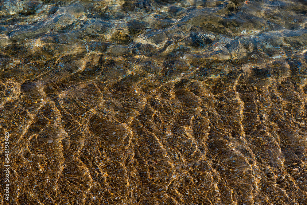 Aquamarine and yellow waves above the texture rivulets of sand on the shoreline of the Mediterranean coast in Israel.