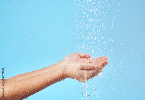 Shower, water and hands of a woman cleaning, saving and catching liquid against blue studio background. Sustainability, wellness and person with care for body, grooming and hygiene with mockup space