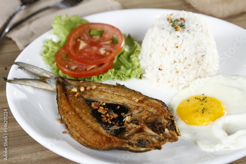 Filipino breakfast of fried bangus (milkfish) with garlic flakes and egg, lettuce, tomato and garlic fried rice