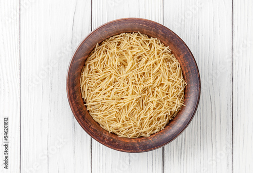Obraz na płótnie Uncooked vermicelli pasta in ceramic bowl on white wooden background w salonie