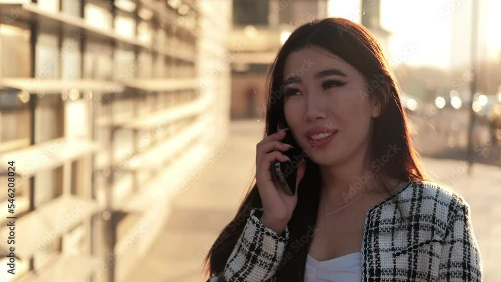 Positive business asian woman talking on the smartphone. Smiling businesswoman calling mobile phone. Portrait of Asian young woman walking in business center. Confident girl. Career people. High Positive business asian woman talking on the smartphone. Smiling businesswoman calling mobile phone. Portrait of Asian young woman walking in business center. Confident girl. Career people. High