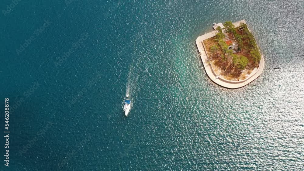 Sailboat passing near small island in Ionian sea Sailboat passing near small island in Ionian sea