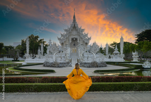 Wat Rong Khun or White Temple at sunset. Tourist girl looking towards the temple. Thailand's top travel destinations. Chiang Rai, Thailand photo