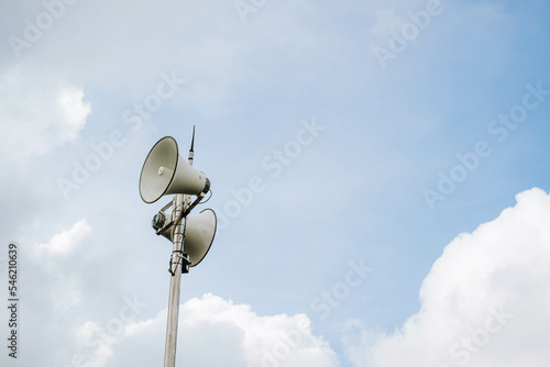 White megaphones mounted on poles in outdoor against blue sky background photo