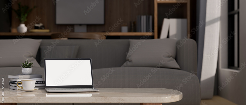 Laptop mockup and copy space on coffee table over blurred living room with couch in background Laptop mockup and copy space on coffee table over blurred living room with couch in background