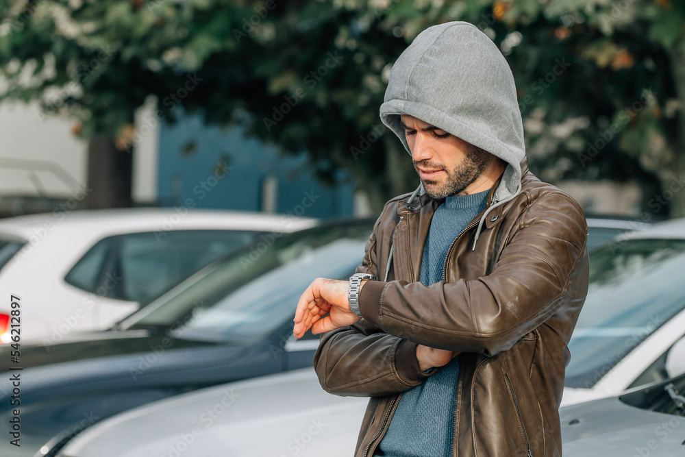 young man looking at his hand watch in the street young man looking at his hand watch in the street