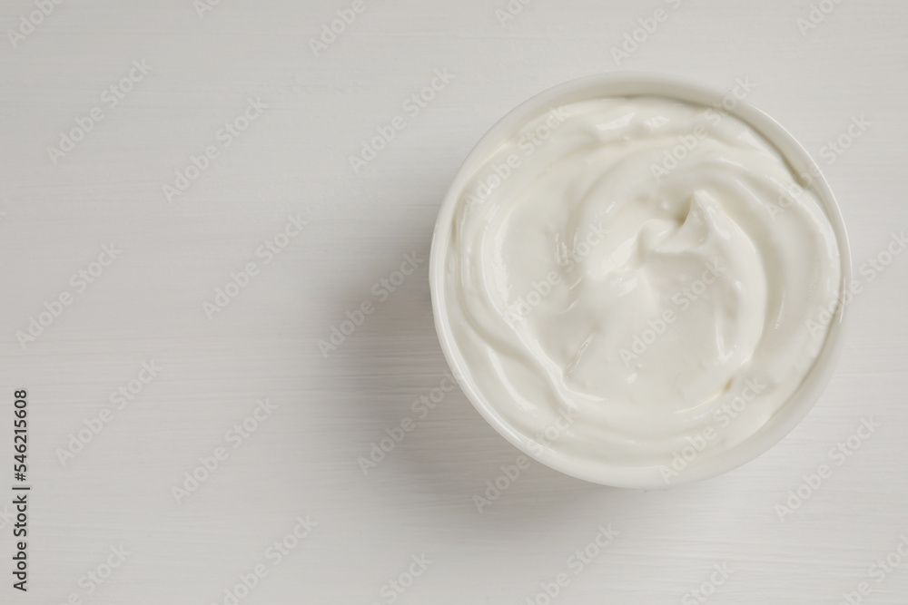 Bowl of fresh yogurt on white wooden table, top view. Space for text Bowl of fresh yogurt on white wooden table, top view. Space for text