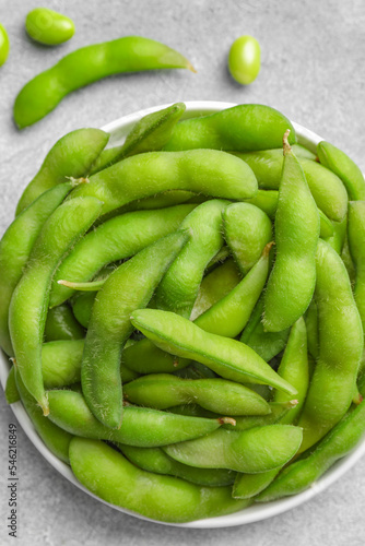 Green edamame beans in pods on light grey table, flat lay