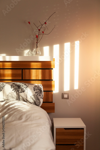 Bedroom with Zebrano wood headboard, with the sun coming through the window.