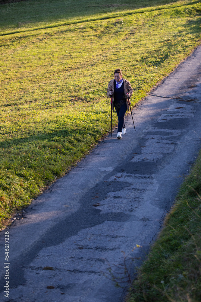 Elder lady nordic walking on a countryside road