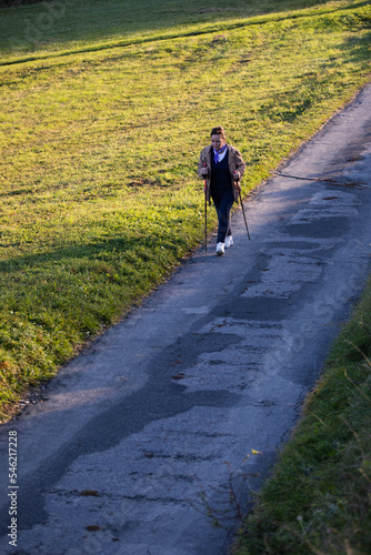 Elder lady nordic walking on a countryside road