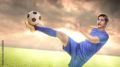 Fototapeta Naklejka Na Ścianę i Meble -  Asian football player man in a blue jersey kicking the ball