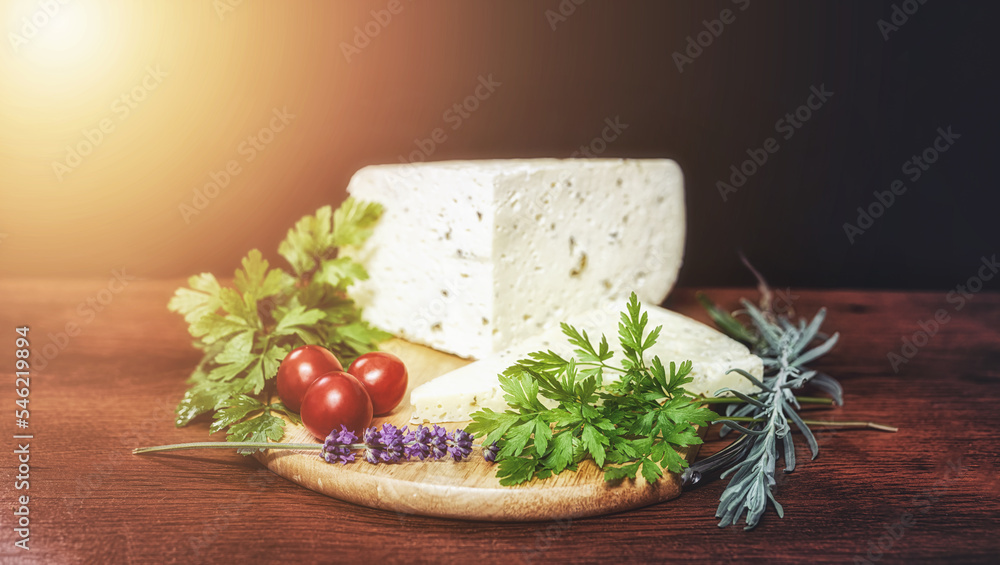 handmade rural cheese on a wooden board with vegetable decoration on meadow background. handmade rural cheese on a wooden board with vegetable decoration on meadow background.