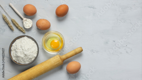 Baking preparation. Rolling pin, eggs and flour on a gray background. 