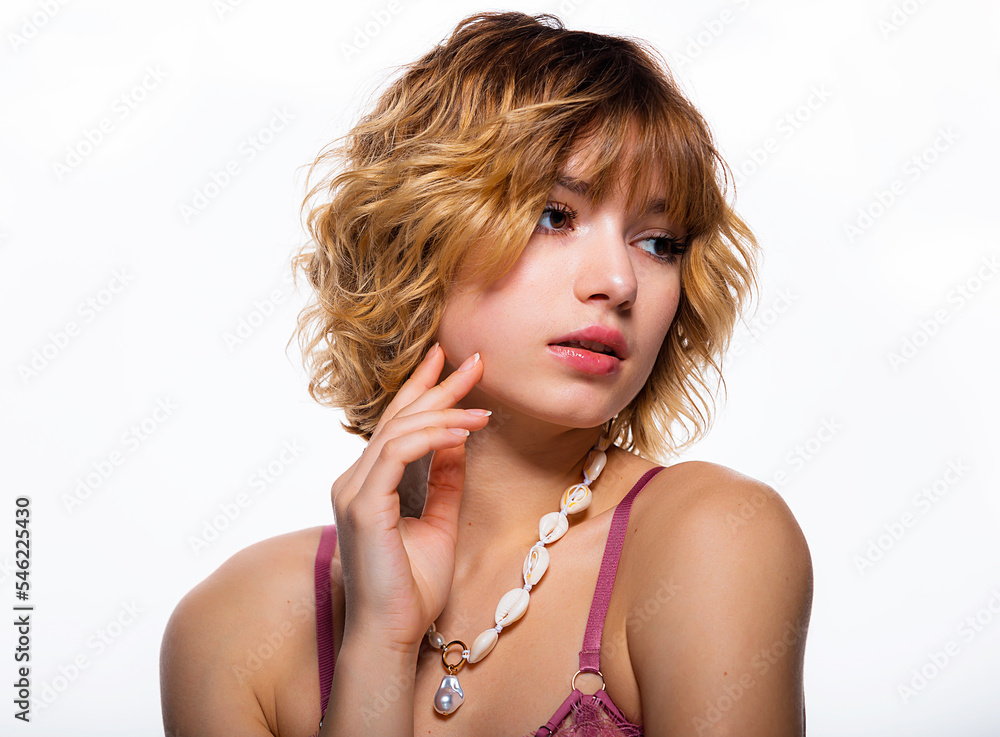 Close up of cute woman face portrait. Beautiful blonde with short hair style and fresh clean skin. Female looking at camera and holds a hand with a natural manicure near the face.