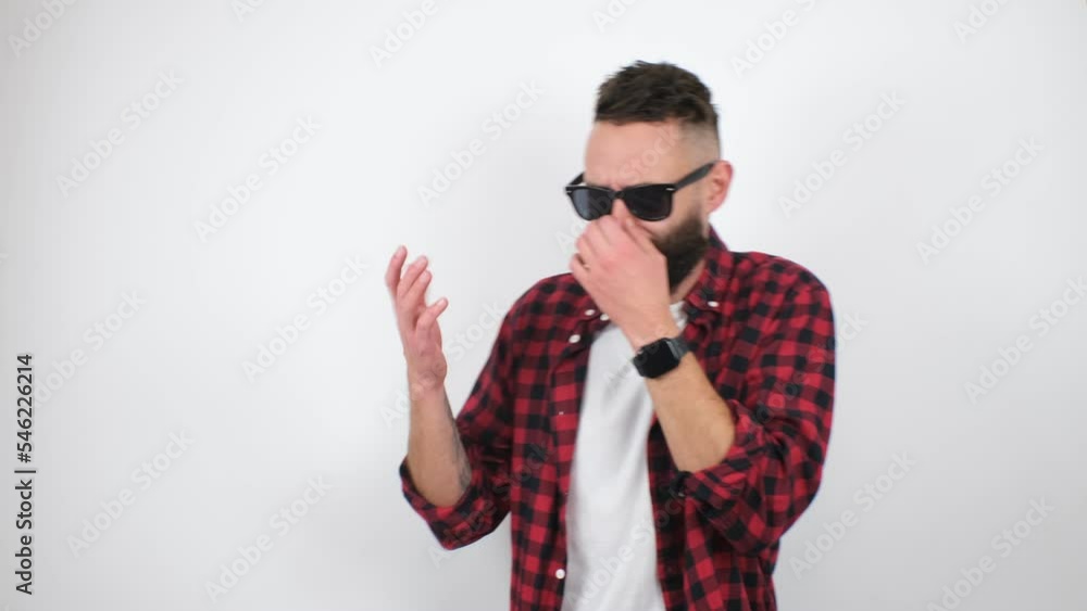 Dissatisfied bearded hipster guy pinches his nose, holding his breath, expressing disgust at the bad smell. The video was shot in a studio on a white background. Dissatisfied bearded hipster guy pinches his nose, holding his breath, expressing disgust at the bad smell. The video was shot in a studio on a white background.