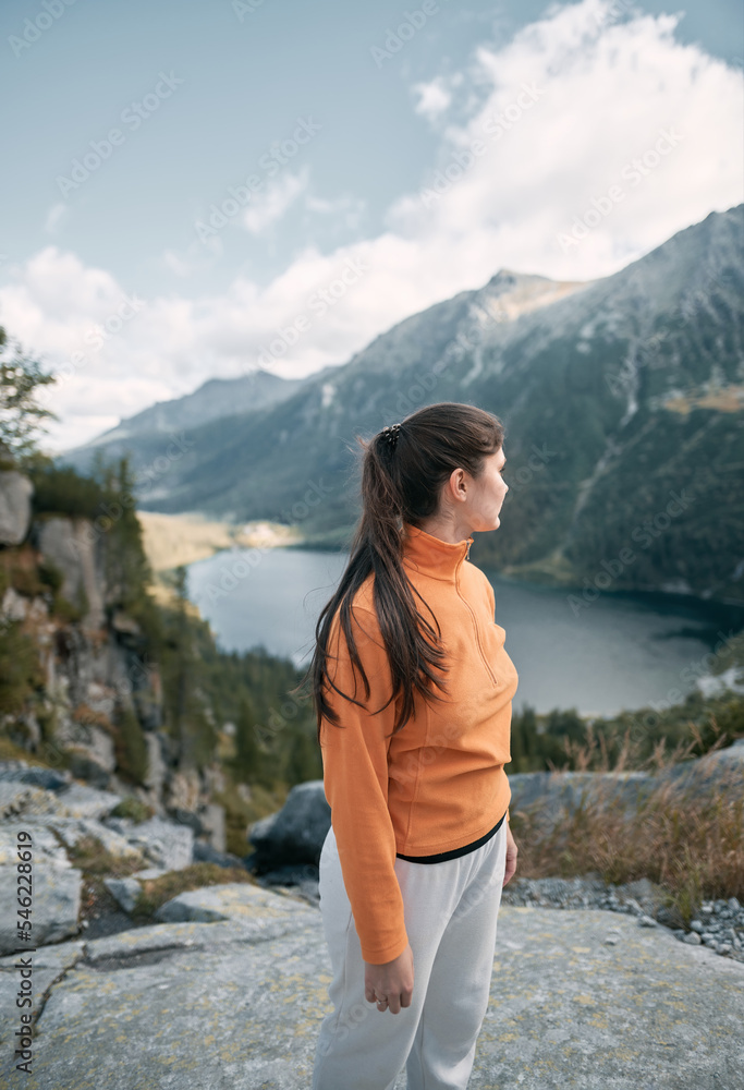 Naklejka premium Happy girl in the mountains. Concept of hiking physical activities making you healthier and happier. Active way of life outdoors concept.