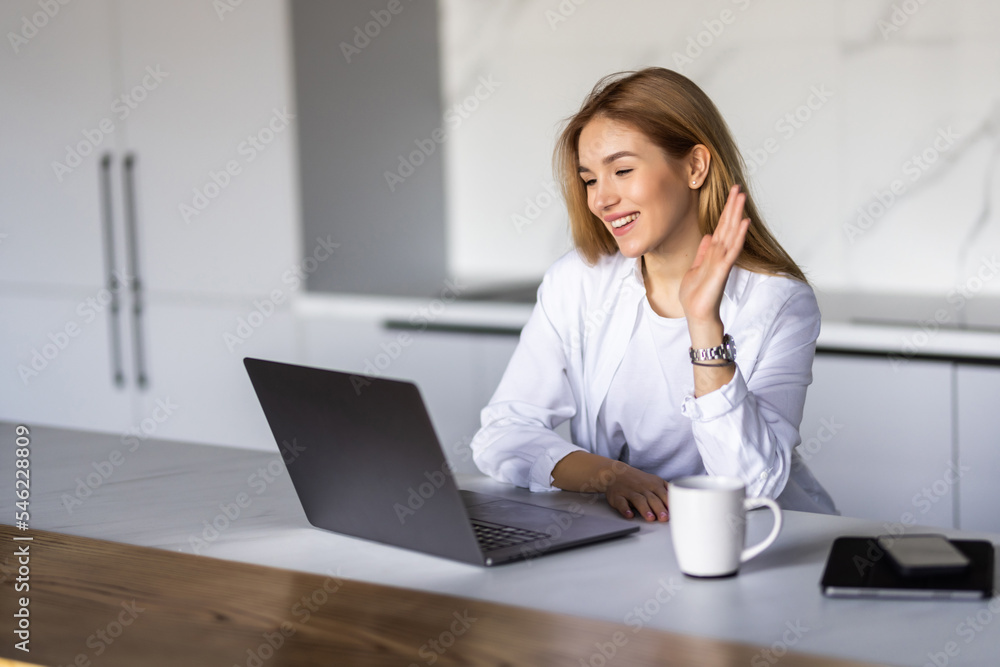 Smiling young woman making video call and heaving a breakfast in her kitchen. Smiling young woman making video call and heaving a breakfast in her kitchen.