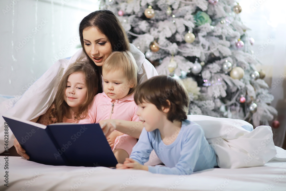 A family with children having fun on the bed under the covers during the Christmas holidays. A family with children having fun on the bed under the covers during the Christmas holidays.