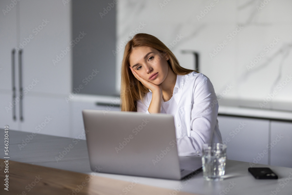 Smiling young woman typing on her laptop in the kitchen Smiling young woman typing on her laptop in the kitchen