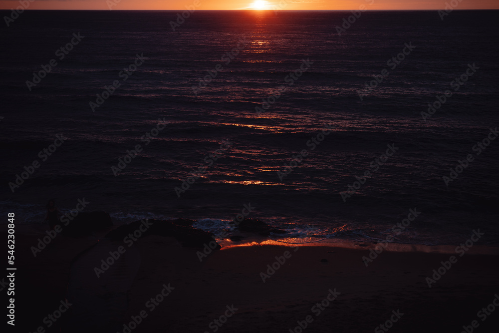 Por do sol na praia com reflexos na agua e tens bem dourados Por do sol na praia com reflexos na agua e tens bem dourados