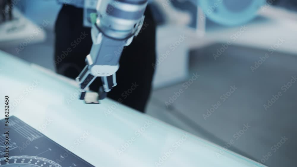 Close Up of a Modern High Tech Robot Arm Picking Up a Microchip from a Table. Robotics Developer Using Virtual Reality Headset and Controllers to Interact with the Robot. Close Up of a Modern High Tech Robot Arm Picking Up a Microchip from a Table. Robotics Developer Using Virtual Reality Headset and Controllers to Interact with the Robot.