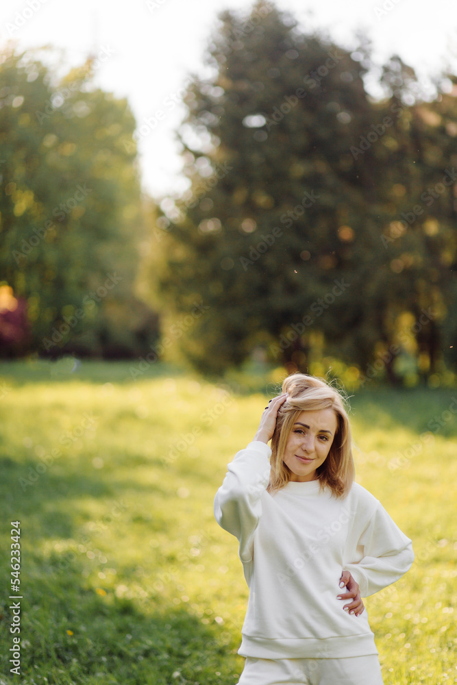Young blonde girl is wearing a white hoodie smiling and walking in the woods Young blonde girl is wearing a white hoodie smiling and walking in the woods