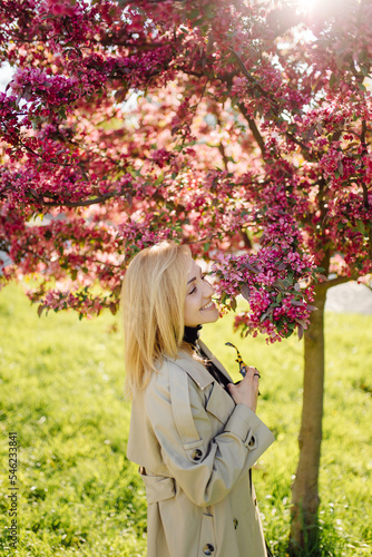 Caucasian blonde woman wearind trench smile happily on sunny spring day outside walking in park photo