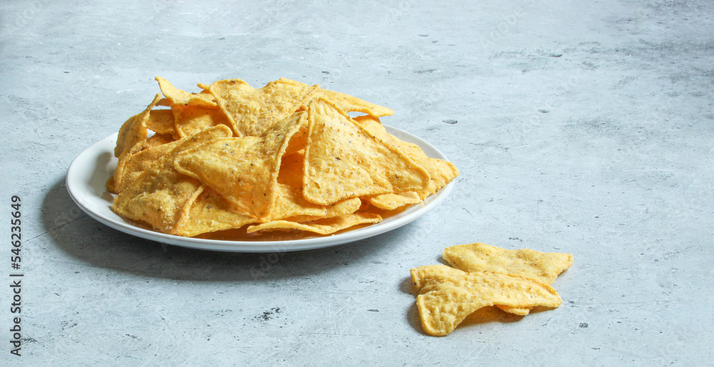 White plate with corn chips nachos on the concrete background. Mexican nachos. White plate with corn chips nachos on the concrete background. Mexican nachos.