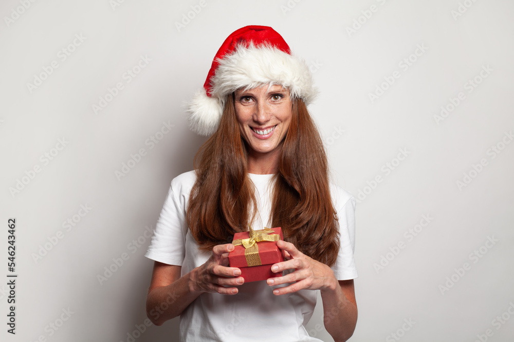 Portrait of happy woman in Christmas hat holding red gift box on white background Portrait of happy woman in Christmas hat holding red gift box on white background