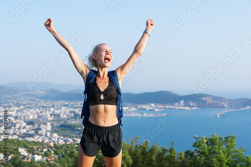 Portrait of a young woman who is happy that she climbed the mountain. Beautiful sea view. Hiking in summer