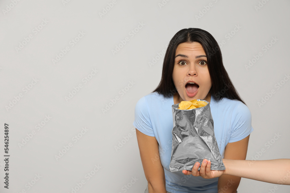 Beautiful young woman with tasty potato chips on grey background, space for text Beautiful young woman with tasty potato chips on grey background, space for text