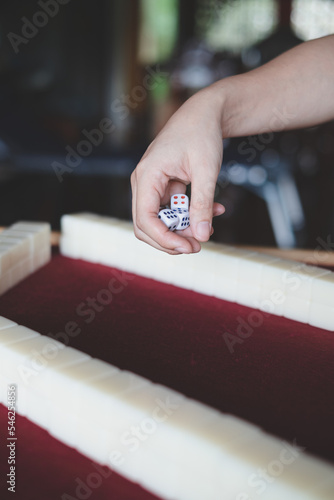 Hands rolling dice, playing Mahjong game. Concept of chinese leisure games traditional, family activity, Hongkong board game, chinese new year fmily time entertainment. Lucky game. photo