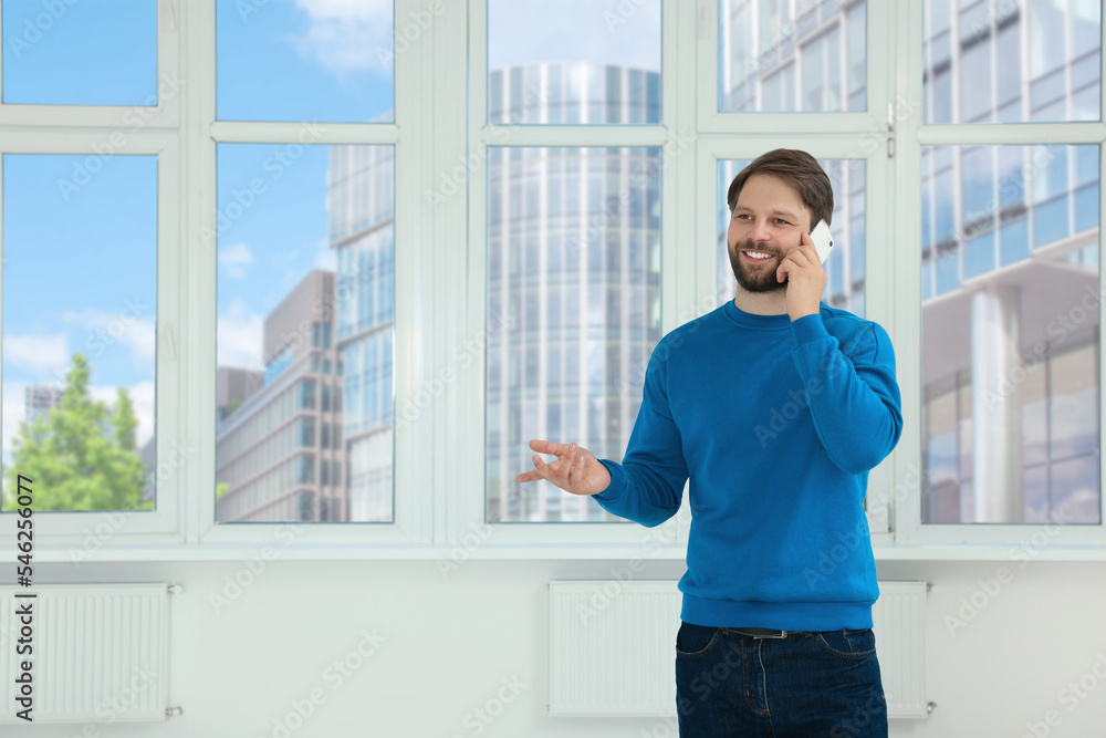 Man in casual clothes talking on phone indoors, space for text Man in casual clothes talking on phone indoors, space for text